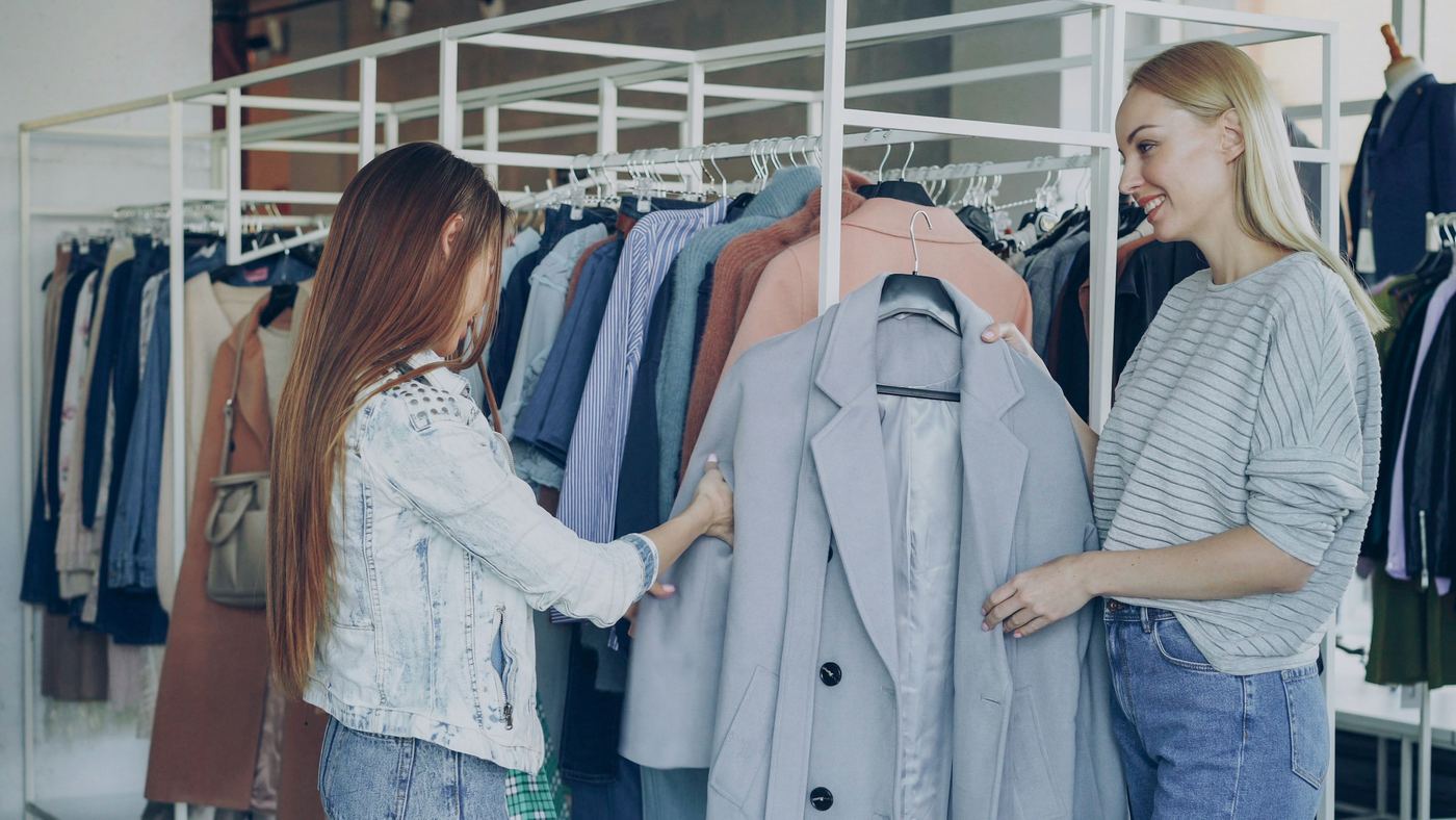 Dos mujeres miran ropa en los percheros de una tienda