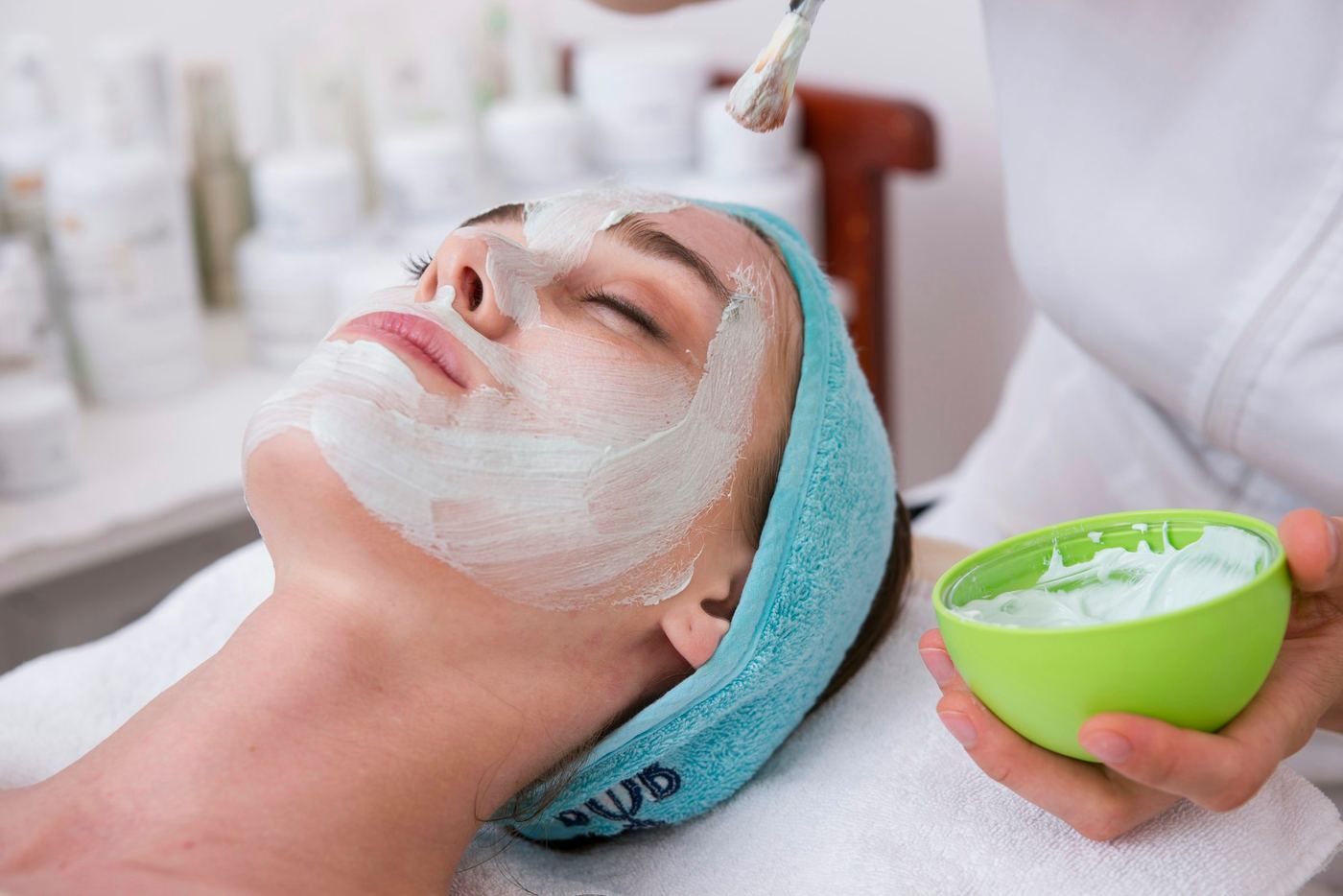 Mujer recostada sobre una toalla con crema facial aplicada en el rostro