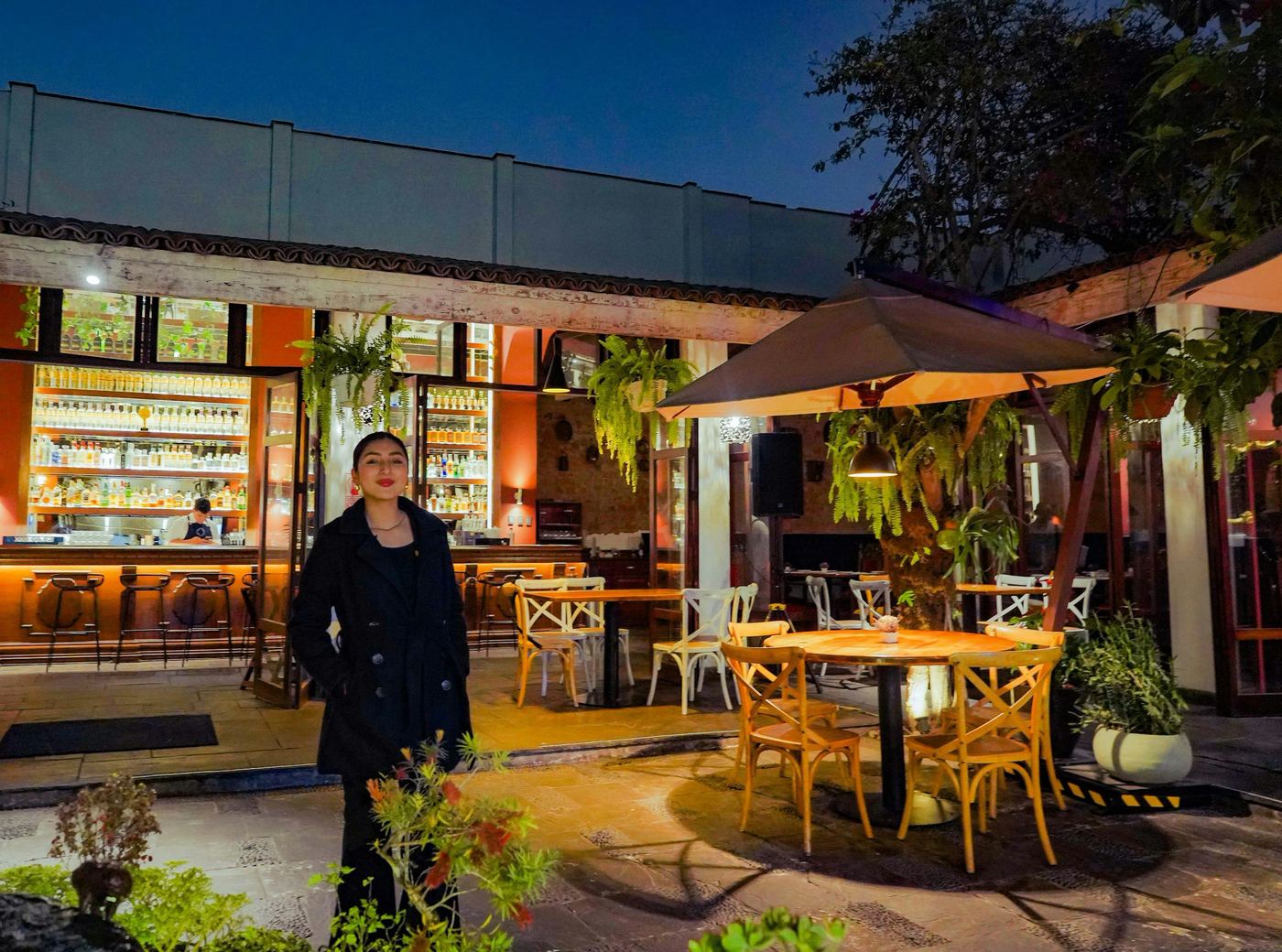 Mujer de pie en el patio de un restaurante iluminado de noche en el centro histórico de Lima