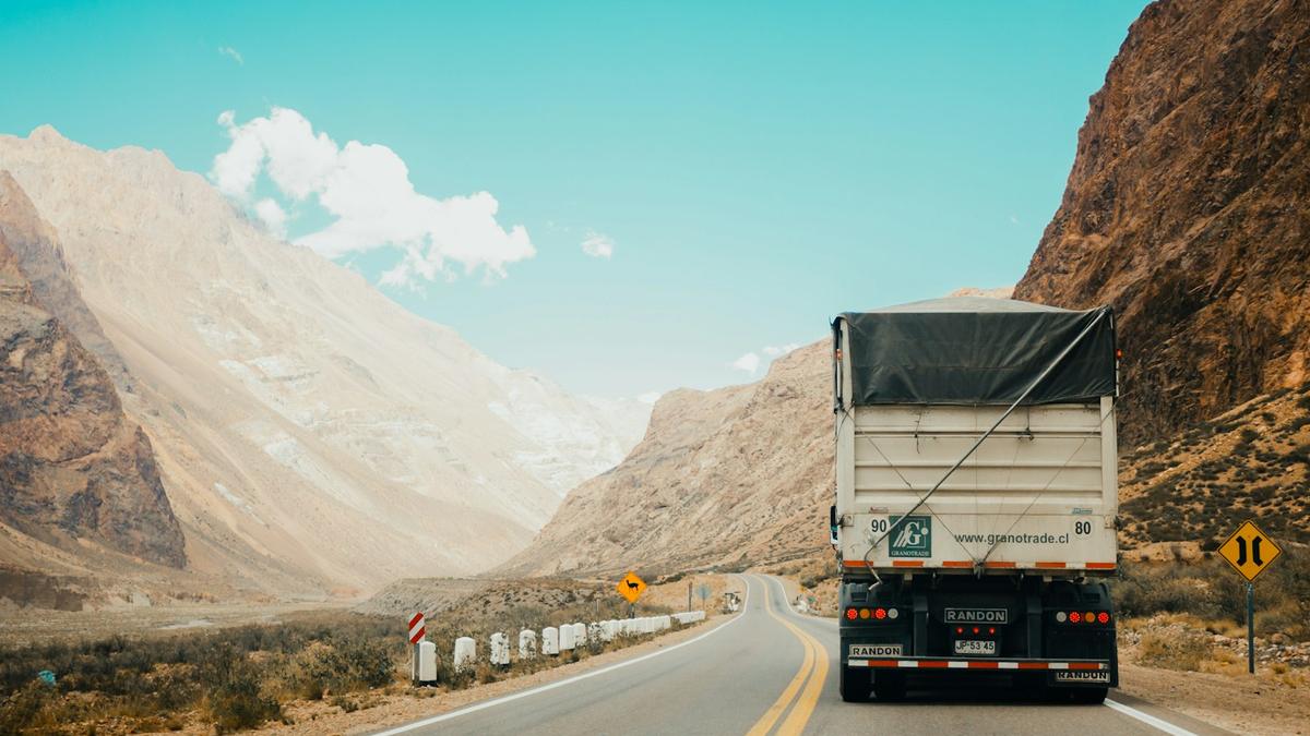Camión de carga en una carretera entre montañas, representando el reclutamiento de conductores de MB Global Logistics