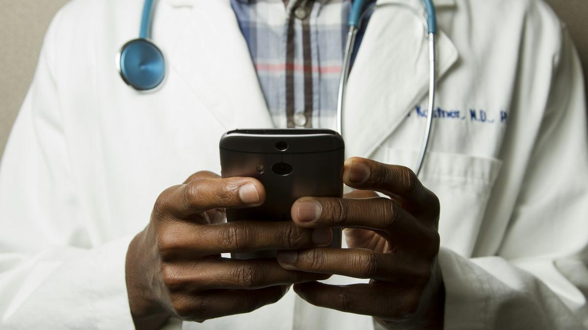 Profesional de la salud con estetoscopio usando un teléfono, representando la operación de un proveedor médico